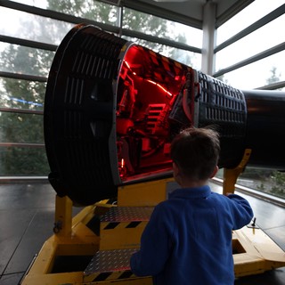 Child Observing Large Telescope Exhibit at Space Center