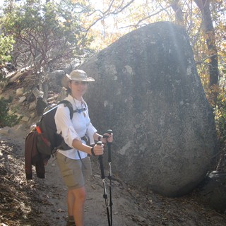 Hiker Pauses Beside Massive Boulder on Trail