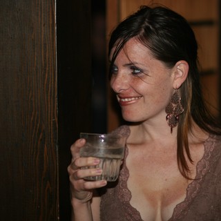 Woman Smiling with Drink at Evening Social Event