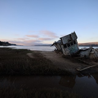 Abandoned Shipwreck at Dusk on Coastal Mudflats