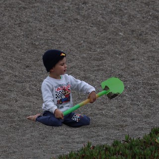 Young Boy Playing with Shovel on Sandy Beach