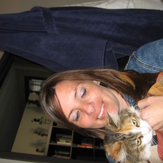 Woman Smiling Warmly While Cuddling Calico Cat