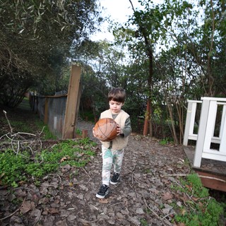 Young Boy Carrying Basketball Through Garden Path
