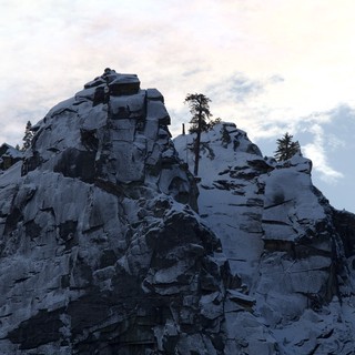 Lone Climber Reaches Summit of Snow-Covered Rocky Peak