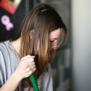 Young Woman Sweeping with Head Bowed Down