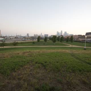 City Skyline and Lush Grass Field