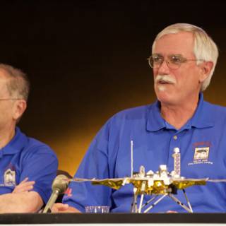 Two Men in Blue Shirts Sitting at Phoenix Landing Press Conference