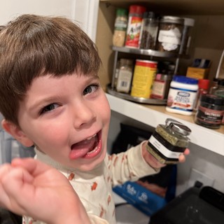 Young Boy Excitedly Tasting Food in Kitchen