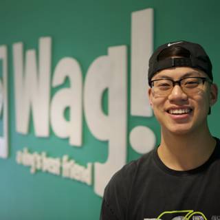 Young Man Poses in Front of Wag Logo