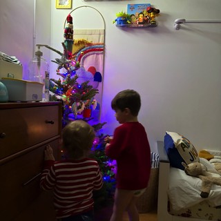 Children Decorating Small Christmas Tree in Bedroom