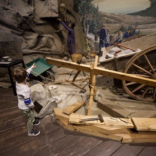 Young Child Exploring Interactive Gold Rush Mining Museum Exhibit