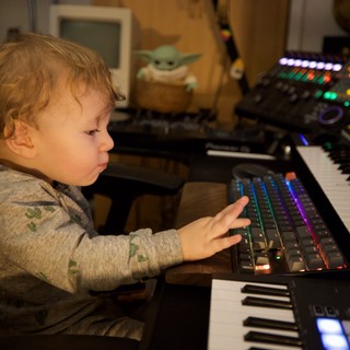 Young Child Exploring Music Production Equipment at Night