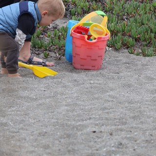 Toddler Explores Sandy Beach with Colorful Toys