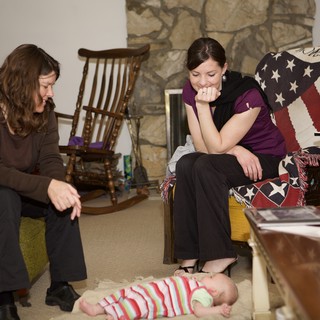 Two Women Admiring a Baby on the Floor