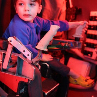 Young Boy Playing Arcade Motorcycle Game in Red Light