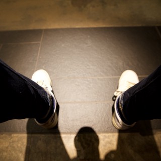 First-Person View: White Sneakers on Tiled Floor