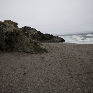 Dark Sand Beach Meets Dramatic Coastal Rock Formation