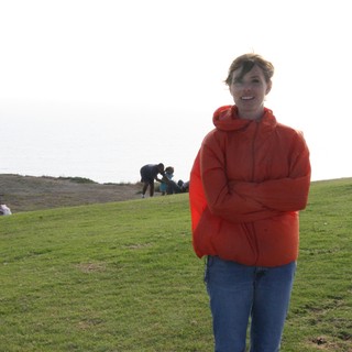 Woman in Red Hoodie on Coastal Hillside at Dusk