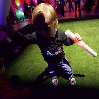 Child Dancing with Glow Stick at Baby Rave Event