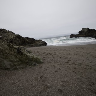 Rugged Cove Beach with Dark Sand and Crashing Waves