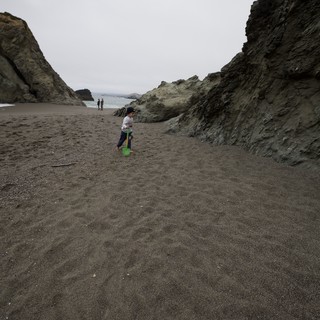 Young Explorer with Shovel on Dark Sand Beach