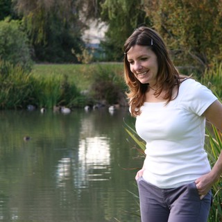 Woman Smiling by a Tranquil Park Pond