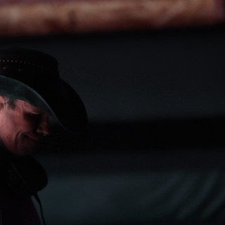 Tattooed Performer in Black Cowboy Hat Under Stage Lights