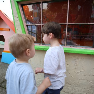 Two Brothers Peering into Colorful Playhouse Window