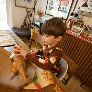 Child Enjoying Christmas Pizza with Dinosaur Toy
